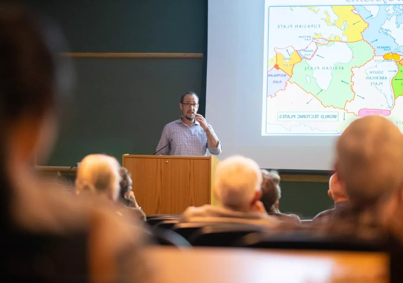 Professor next to map speaking to seated audience